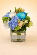 Colorful flower arrangement in a decorative glass vase on a beige background