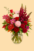 Bouquet of colorful flowers in a clear vase on a beige background