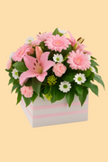Floral arrangement with pink flowers in a box on a beige background